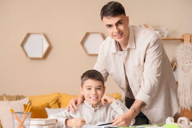 Erkek öğretmeni olan küçük çocuk evde ders çalışıyor.