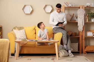 Erkek öğretmeni olan küçük çocuk evde ders çalışıyor.