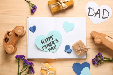 Tebrik kartı, defter, ahşap arabalar ve kahverengi ahşap arka planda çiçekler olan hediye kutuları. Babalar günü kutlaması.