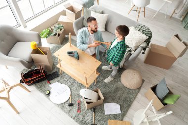 Baba ve oğlu evde raf montajı yapıyorlar.