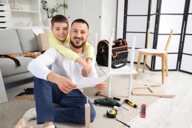 Babası talimatlarla ve oğlu evde mobilya montajı yapıyor.