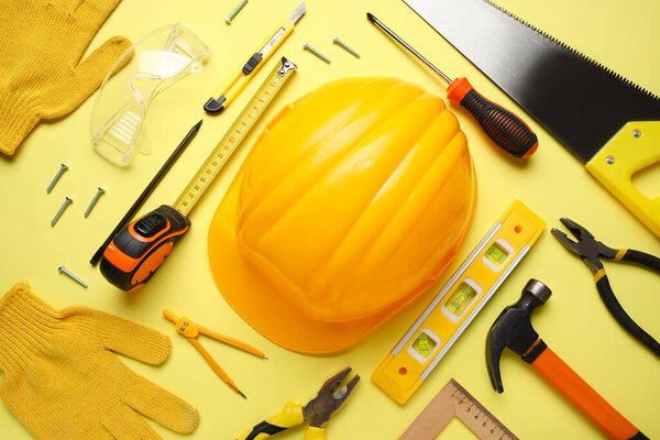 Организация различных строительных инструментов и каски на желтом фоне