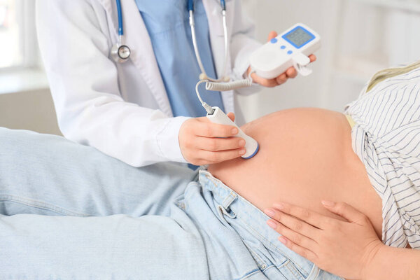 Молодая беременная женщина с фетальным доплером в клинике
