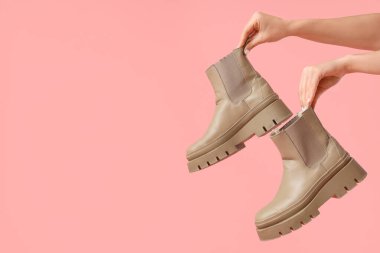 Pembe arka planda bej çizmeli kadın elleri