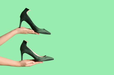 Yeşil arka planda yüksek topuklu kadın elleri