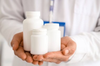 Ofisinde ilaç şişeleri olan erkek doktor, yakın plan.