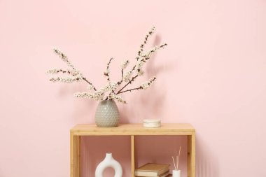 Odanın içinde çiçek açan dalları olan vazo.