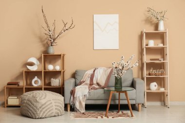 Odanın içi kanepe, raflar ve çiçek açan dallarla dolu.