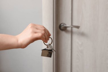 Kapının yanındaki yeni dairesinin anahtarıyla kadın eli, yakın plan.