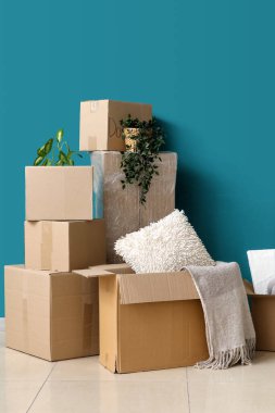 Taşındığı gün mavi duvarın yanındaki karton kutular.