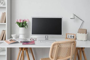 Lale, dergi ve boş bilgisayar monitörlü vazo.