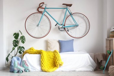 İçinde yatak, bisiklet ve spor aletleri olan hafif ergen odasının içi.