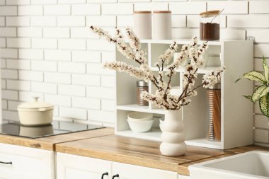 Mutfaktaki ahşap masada güzel dalları, baharatları ve tabakları olan bir vazo.