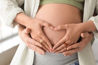 Mutlu hamile çift evde sarılıyor, yakın çekim.