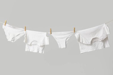 Temiz giysiler gri arka planda çamaşır ipine asılı.