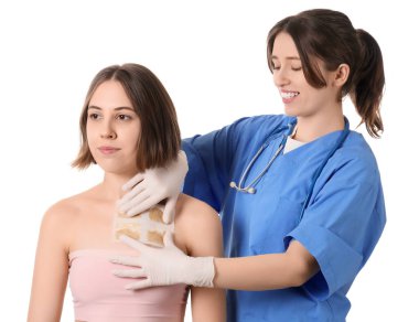 Kadın doktor, beyaz arka planda hastanın göğsüne hardal yapıştırıyor.