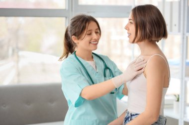 Kadın doktor klinikte hastanın göğsüne hardal yapıştırıyor.