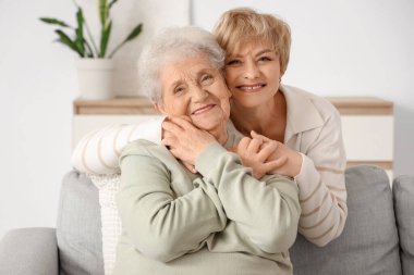 Olgun bir kadın evdeki kanepede annesine sarılıyor.