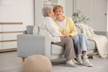 Evdeki kanepede kızını öpen kıdemli bir kadın. Anneler Günü kutlaması