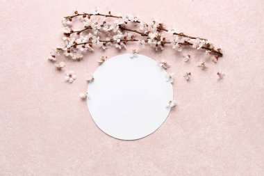 Güzel çiçek açan ağaç dalları ve açık pembe arka planda çiçekler olan boş bir kart.