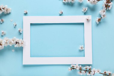 Güzel ağaç dalları ve mavi arka planda çiçekler olan kağıt çerçeve.