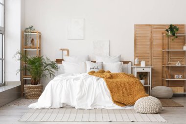 Katlanan ekran, raf üniteleri ve bitkilerle aydınlık yatak odasının içi