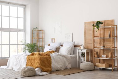 Katlanan ekran, raf üniteleri ve bitkilerle aydınlık yatak odasının içi