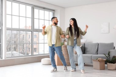 Taşındığı gün odada dans eden mutlu genç çift.