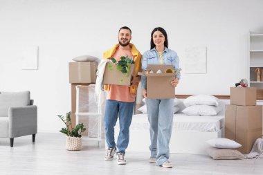 Taşındığı gün yatak odasında kutu taşıyan mutlu genç çift.