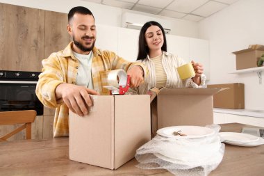 Mutlu genç çift taşınma gününde mutfakta bulaşık topluyor.