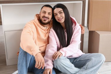 Mutlu genç çift taşınma gününde mutfakta oturuyor.