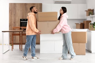 Taşındığı gün mutfakta kutu taşıyan mutlu genç çift.