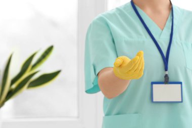 Pencerenin yanındaki tıbbi eldivenli kadın doktor, yakın plan.