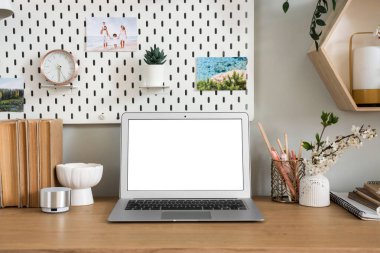 Boş dizüstü bilgisayar ve vazo. Ofiste çiçek açan dallar var.