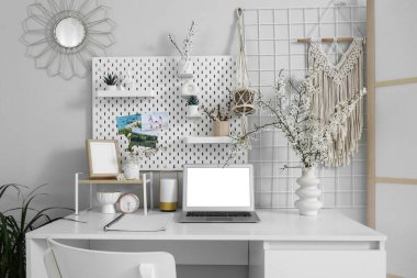 Çalışma yeri, tahta ve vazolarda çiçek açan dallarla aydınlık ofisin içinde.