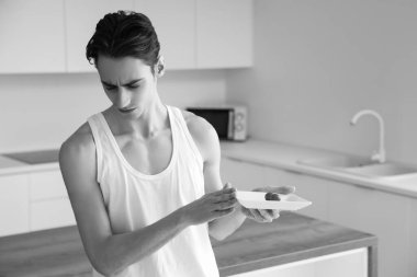 İştahsızlığı olan genç adam mutfakta yemek yemeyi reddediyor.