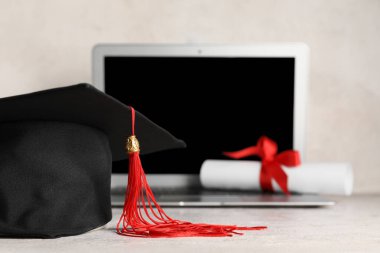 Modern dizüstü bilgisayarı ve beyaz arka planda diploması olan havan mermisi tahtası.