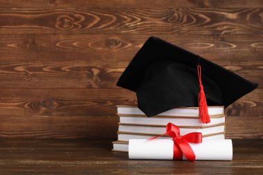 Tahta arka planda kitap yığını ve diploması olan havan topu tahtası.