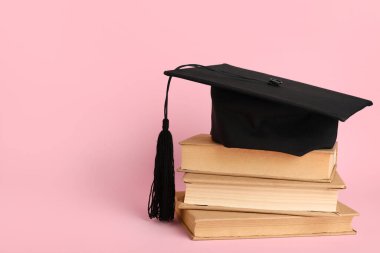 Pembe arkaplan üzerine kitap yığını olan havan topu tahtası