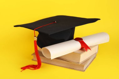 Sarı arka planda kitap ve diploması olan havan mermisi tahtası