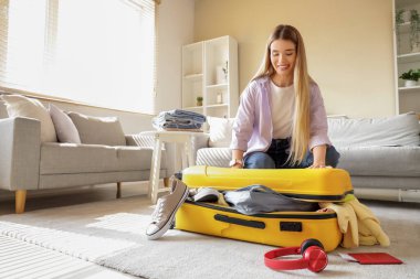 Bayan turist valizini evde kapatmaya çalışıyor.
