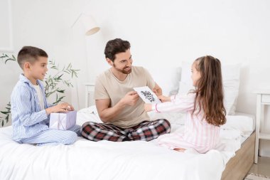 Mutlu baba yatak odasında küçük çocuklarından hediyeler alıyor.