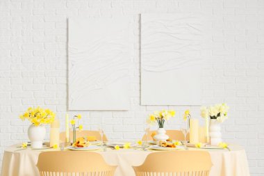 Narcissus çiçekleri, mumları ve bardakları olan zarif bir masa.