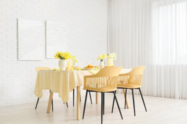 Hafif yemek odasında narsisli güzel çiçekler olan zarif bir masa.