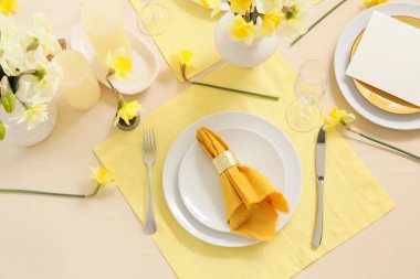 Narcissus çiçekleri ve tabakta katlanmış peçeteyle zarif bir masa.