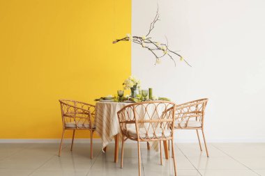 Narcissus çiçekleri, mumlar ve hafif yemek odasında sallanan ağaç dalları olan zarif bir masa.