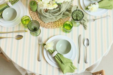 Narcissus çiçekleri, bardakları ve mumları olan zarif bir masa.