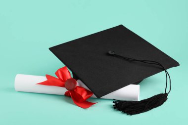 Mezuniyet şapkası ve turkuaz arka plan diploması.