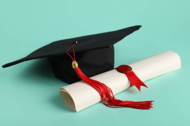Mezuniyet şapkası ve turkuaz arka plan diploması.