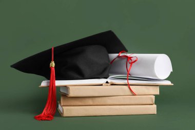 Mezuniyet şapkası, kitaplar ve yeşil arka plan diploması.